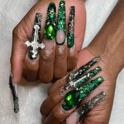 Cynthia Erivo with Elphaba inspired long nails, which include gem accents, fishnet details, silver charms, and green nail polish.