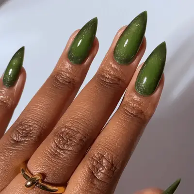 Green nails with a sparkly black polish aura art.