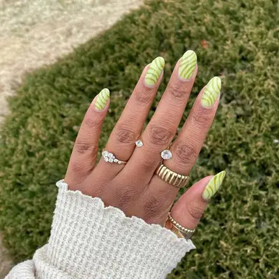 Light sage green manicure with darker sage green swirl lines.