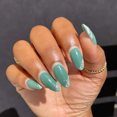 Sage green manicure with white tie dye tips and gold sun and star decals.