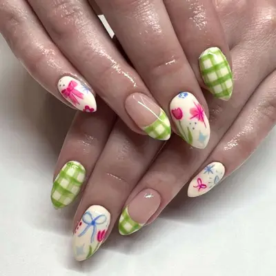 Nail design with green plaid, green plaid French tips, and white nails with flower, heart, star, and sparkle decals.