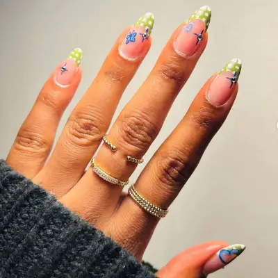 French manicure with green plaid tips and sparkle, butterfly, and heart decals.
