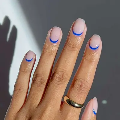 a milky manicure with cobalt blue cuticle cuffs