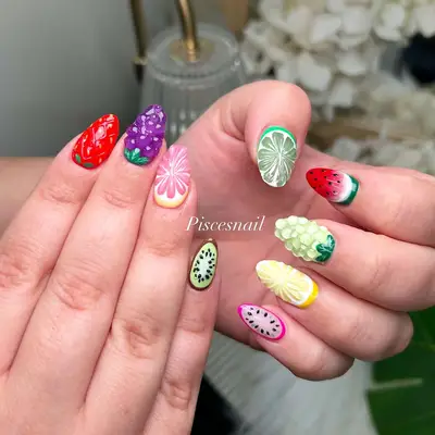 Hand with colorful nail art themed with various fruit designs including strawberry, grape, watermelon, and lime