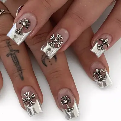 A close up of short nails with a silver French and gothic punk charms.