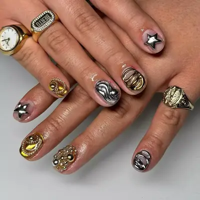 A close up of short nails with mixed 3D charms of gold and silver.