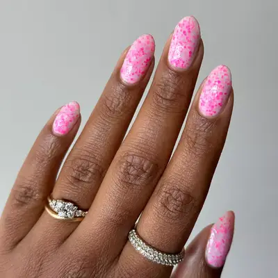 Short round nails with baby pink polish and hot pink splatter on top 