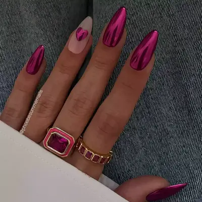 Hand with long chrome pink nails and pink and gold rings