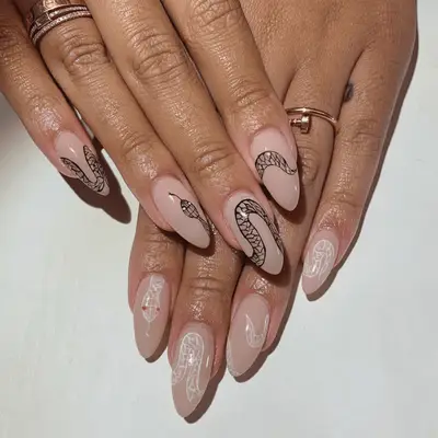 Mismatch manicure with black snake nail art on one hand white snake nail art on the other.