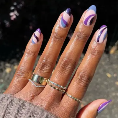 Manicure with curves and arcs in different shades of purple.