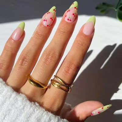 French manicure with green almond-shaped tips and cherry-covered accent nails