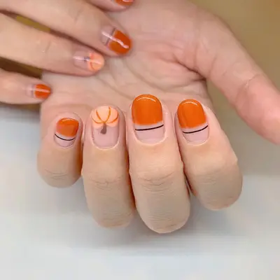 Negative space orange and black nail design with pale pumpkin accent nails