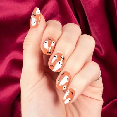 Orange manicure with black bat and white ghost designs