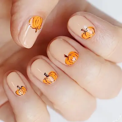 Nude nail design with pumpkin design near cuticle