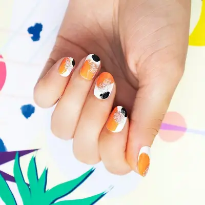 White, orange, and black abstract paint splotches nail design