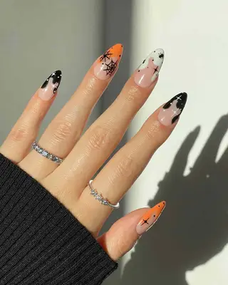 Long almond shaped nails with black, white, and orange drip French tips and spider nail art.