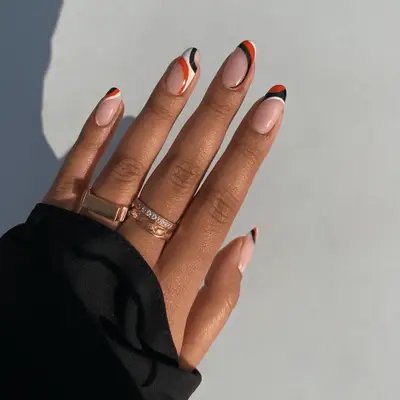 Muted orange manicure with negative space cuticle half moons and black Chanel logo accent