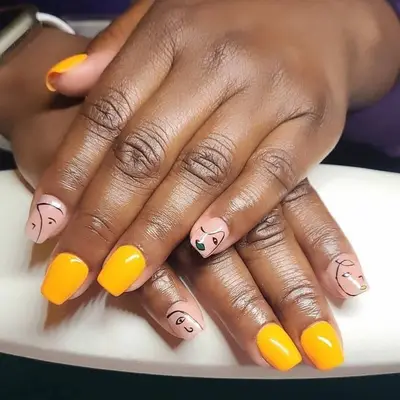 Yellow-orange manicure with nude and black Picasso face accent nails