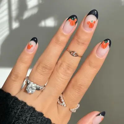 Close up of black French tip nails with Mickey Mouse-shaped pumpkin decals.