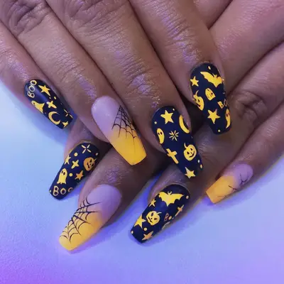 Close up of neone orange and black nails with halloween art, including spiderwebs, pumpkins, and crosses.