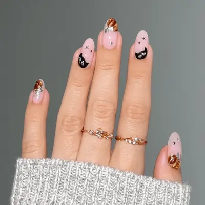 Close up of nude nails with orange chrome pumpkin and black cat nail art.