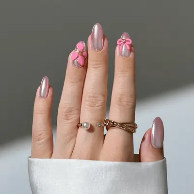 Round nails with pink chrome nail polish and neon pink 3D bows