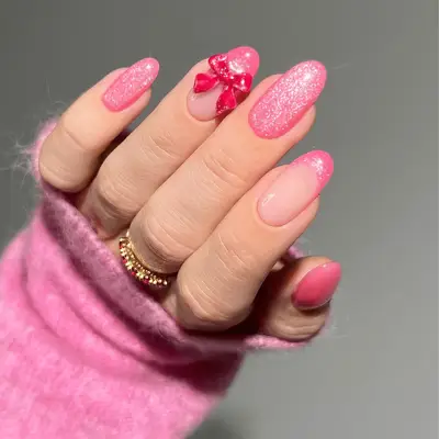 Glittery pink nails with a hot pink bow embellishment