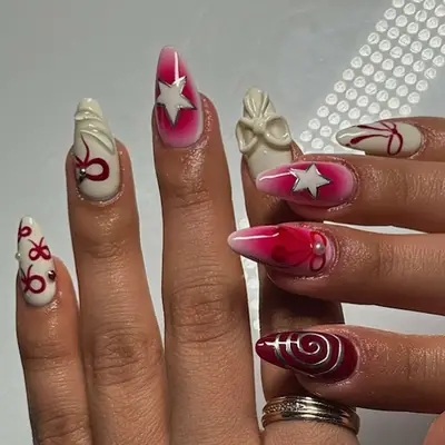 Red and cream-colored nails with swirls and bows