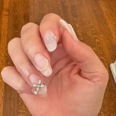 Lana Del Rey nude manicure with big silver bedazzled 3D bow accent