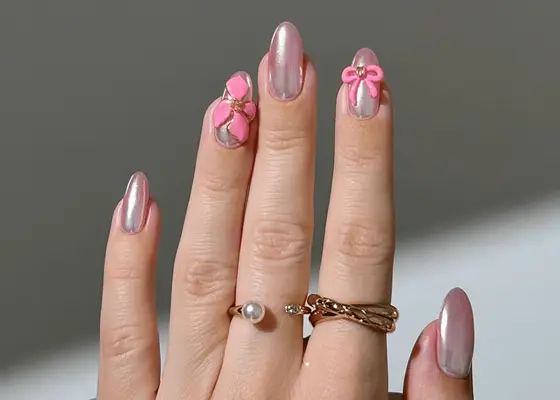 Round nails with pink chrome nail polish and neon pink 3D bows