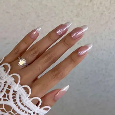 A chrome French manicure with interlinking hearts at the base of an accent nail