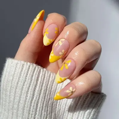A yellow French manicure with yellow flower accents