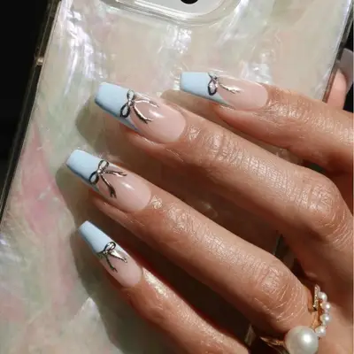 Square-shaped nails with blue-tipped French manicure accented with silver bows