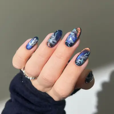 Midnight marbled navy blue oval-shaped manicure with white and copper accents 