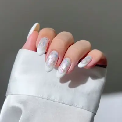 A hand showing manicure with iridescent nail polish and a white fabric sleeve