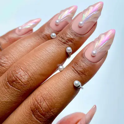 Manicured nails with pearl and seashell-inspired design, adorned with pearl rings