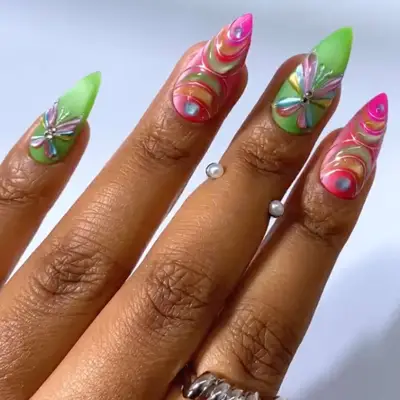 Hand with bright nail art featuring colorful patterns and butterfly designs