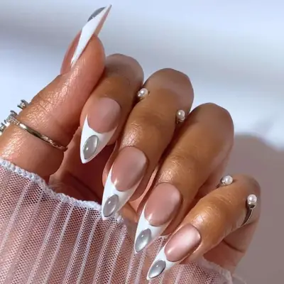 Hand displaying nail art with moonstone decorations and pearls