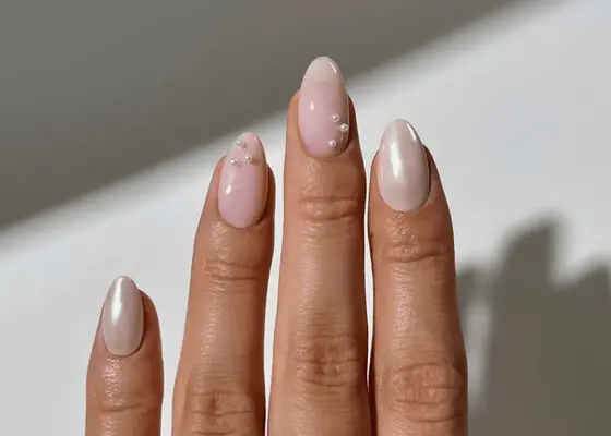 Hand with manicured nails featuring pearl embellishments