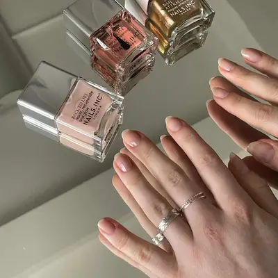 Close up of nail polishes and hands wearing a base coat