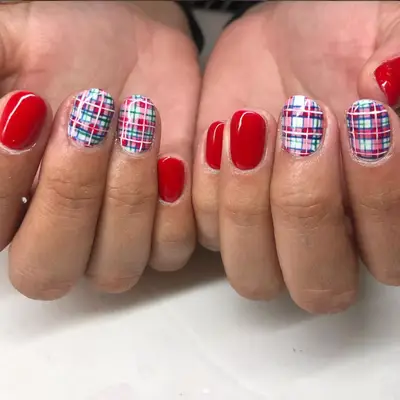 Short red manicure with plaid accent nails
