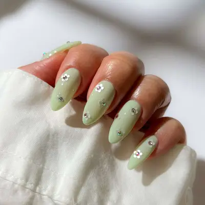 a dainty pistachio manicure with gemstone daisies 