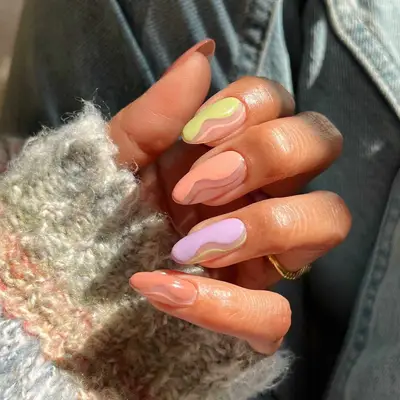 a soft skittle manicure in light, bright shades with negative space and swirls