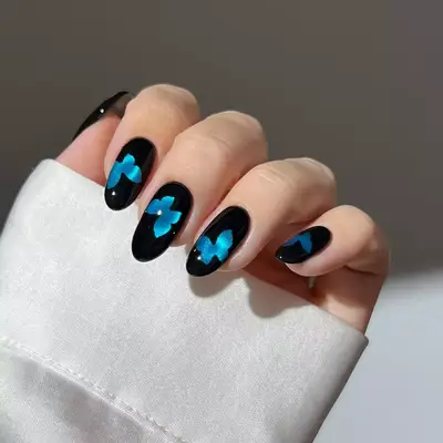 Model with black nails and a blue butterfly design
