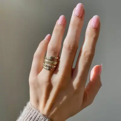 Model with light pink nails with thin gold design