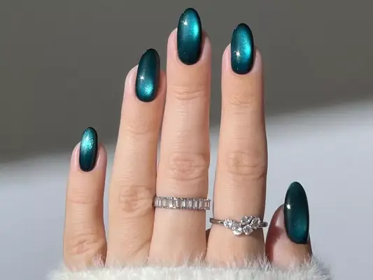 Model with teal nails that have a cat-eye effect