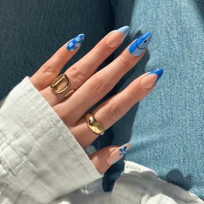 blue theme nails with checkered smiley face and floral designs and french tip accents