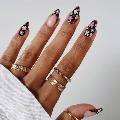 black nails with colorful daisy design and french tip accent nails