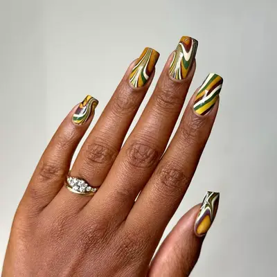 Green, brown, yellow, and white striped nails with marble effect