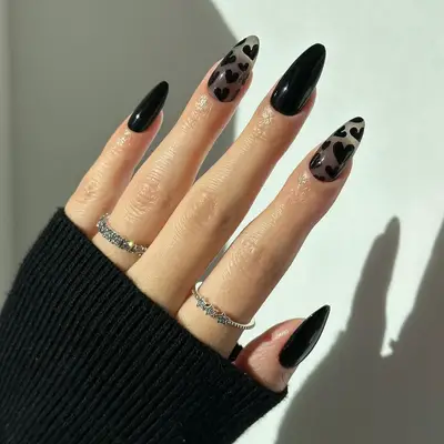 Black nails with black hearts over sheer gray polish